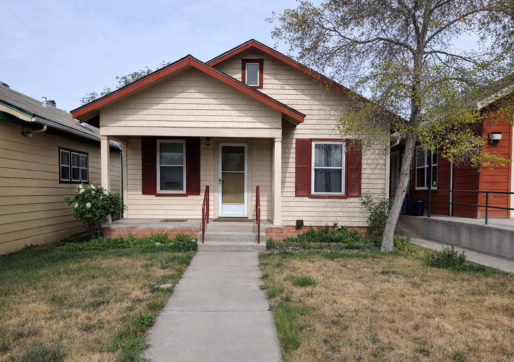For Sale or Lease-222 Oak Ave, Eaton, CO 80615. A small beige house with red trim and shutters, a covered front porch, and a concrete walkway leading to the entrance. The yard has patchy grass and a tree on the right side near the house.